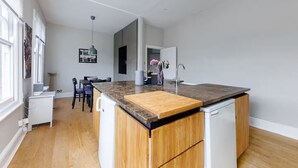 Een moderne keuken met een centraal eiland, houten kastjes en een inbouwvaatwasser.