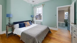 Een slaapkamer met een groot bed, een kroonluchter, een raam en uitzicht op buiten.