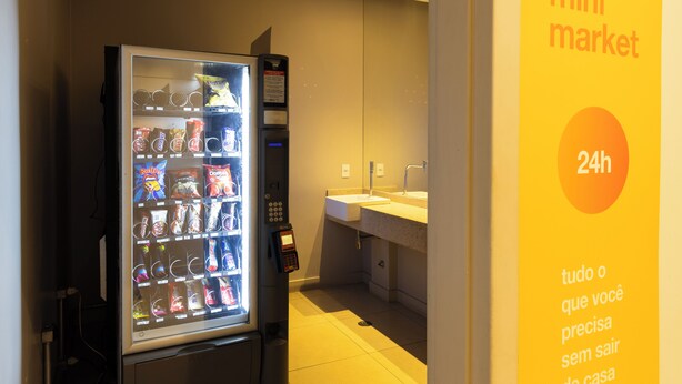A vending machine with snacks and a small sink area. - Moderno com AC piscina e academia (São Paulo)