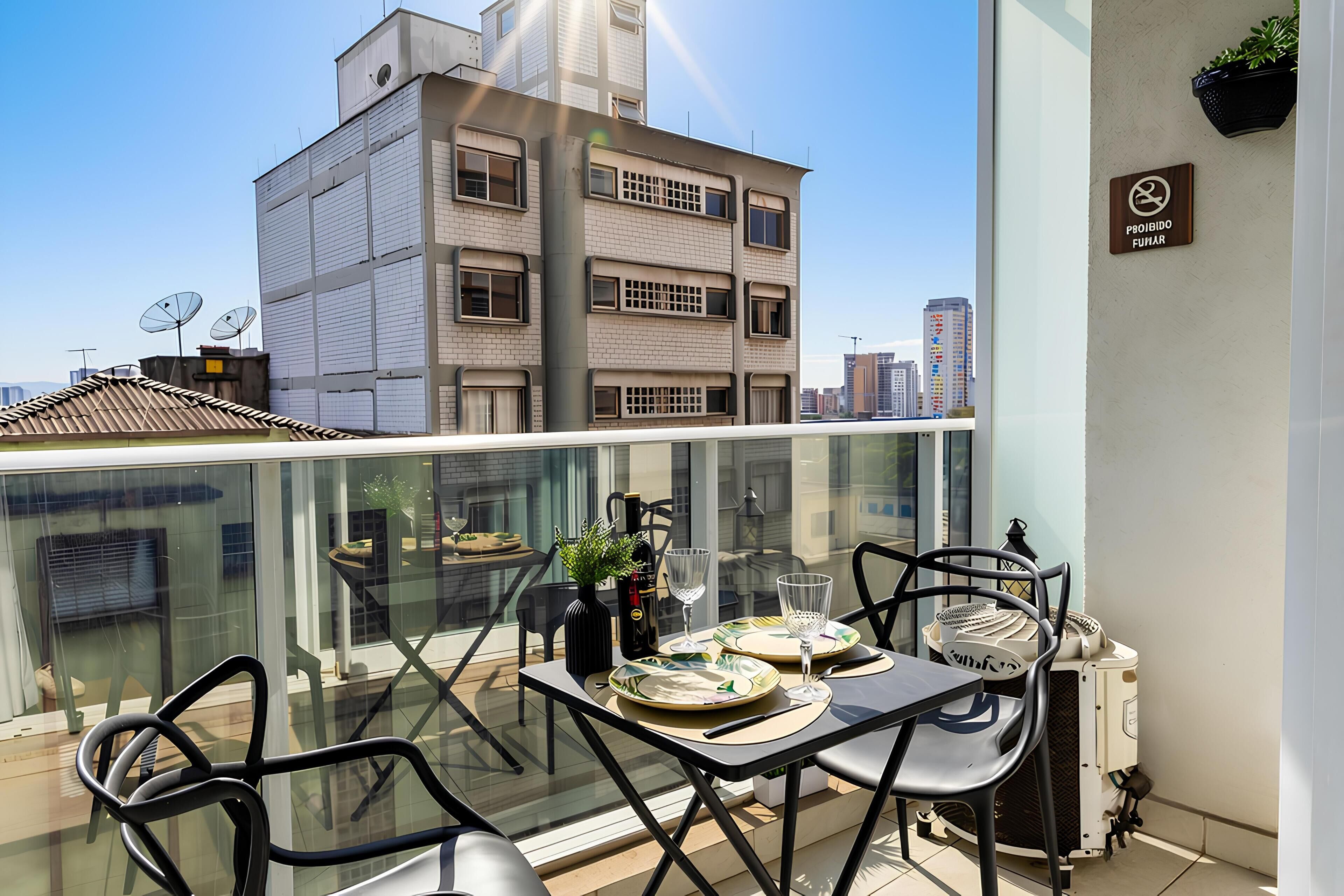 Ein Balkon mit Tisch für zwei Personen, Stühlen, einem Blumentopf und einer Weinflasche.