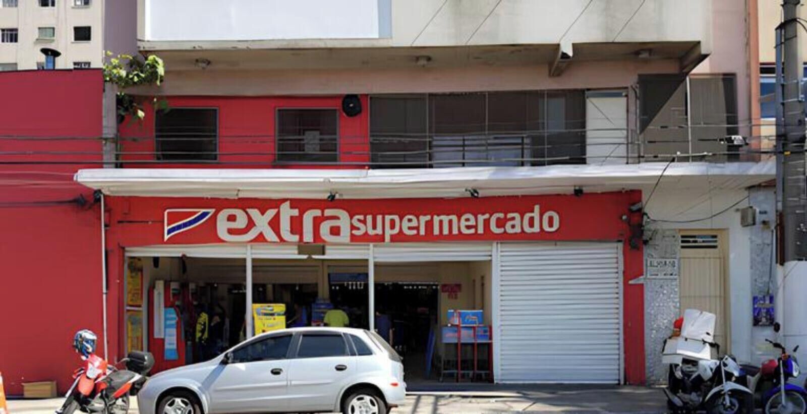 A building with a storefront labeled 'extra supermercado' and a closed shutter door.
