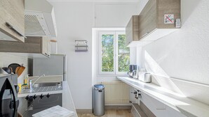 Eine moderne Küche mit Einbauherd, Spüle und einem Fenster mit Blick auf Grünfläche.