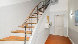 Eine Treppe mit Holzboden und Metallgeländern, eine weiße Tür und eine Wandleuchte.