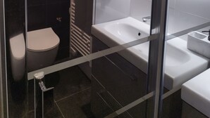 Un baño moderno con cabina de ducha de vidrio, una bañera blanca, inodoro y lavamanos.