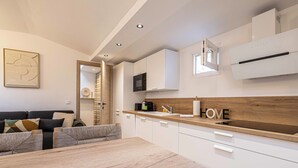 A modern kitchen with white cabinets, a wooden countertop, and a built-in microwave. - Warm apartment near Palais Festivals and old port (Cannes)
