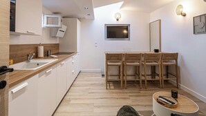 A modern kitchen with white cabinets, wooden countertops, a built-in microwave, and a dining area with a wooden table and chairs. - Warm apartment near Palais Festivals and old port (Cannes)