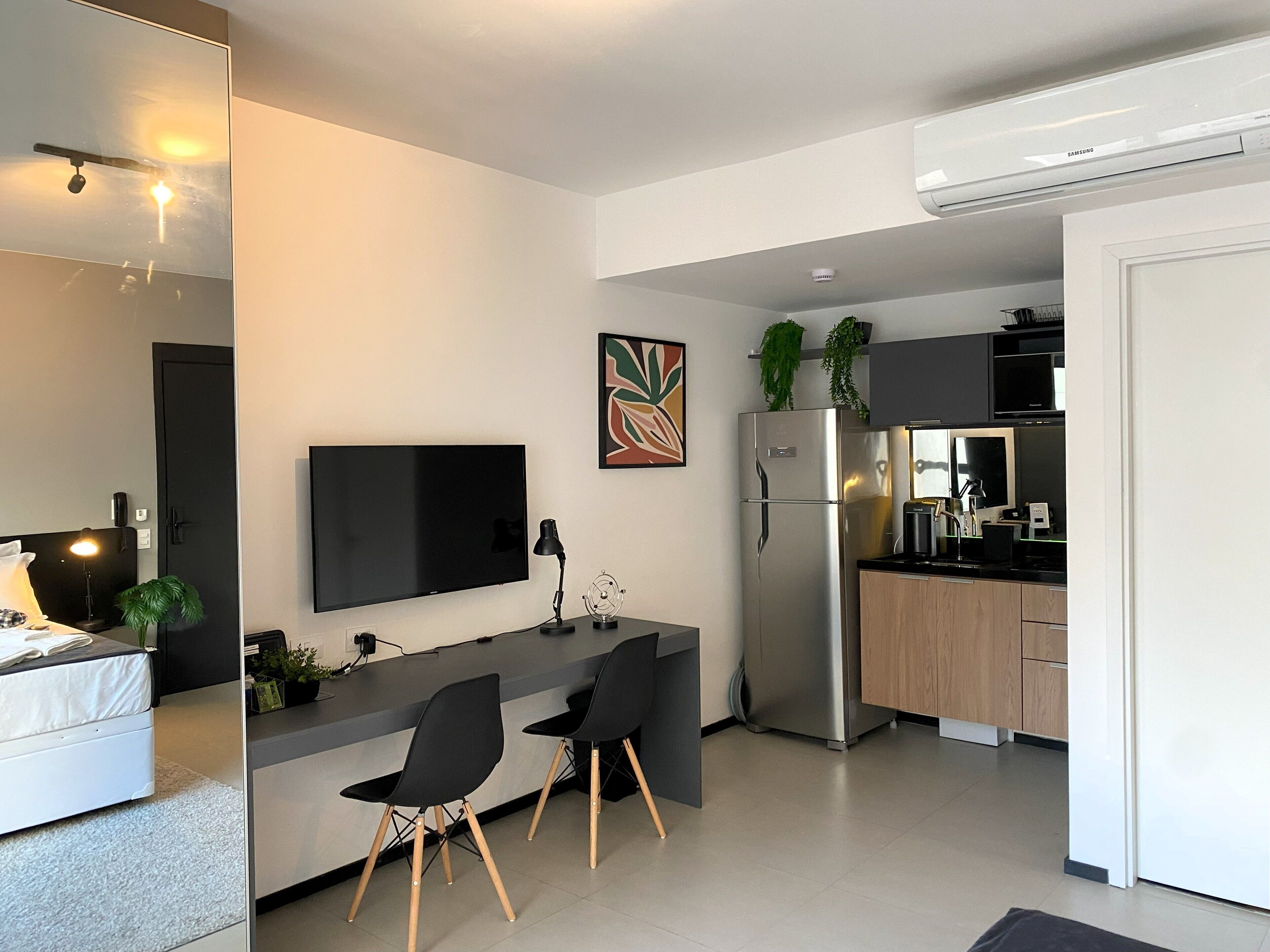 A modern kitchen with a built-in refrigerator, a flat-screen TV, and a dining area with two chairs.