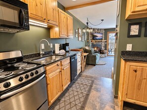 A kitchen with wooden cabinets, a stove, and a microwave. - Slope-Side Pet-Friendly Studio | In-Unit Jet Tub (Lutsen)