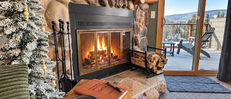 Una chimenea acogedora con un hogar de piedra, un árbol de Navidad y vistas al exterior.