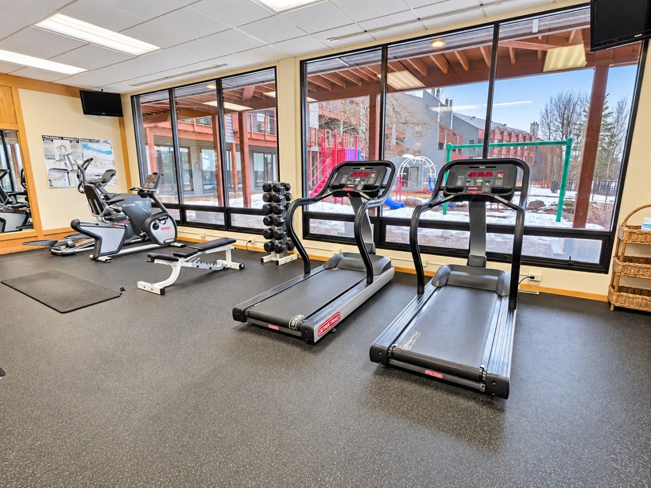 Une salle de sport équipée de tapis de course, d’un vélo d’appartement et d’appareils de musculation.