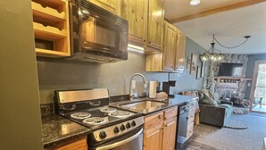 A kitchen with a stove, sink, and wooden cabinets. - Slope-Side Pet-Friendly Studio | In-Unit Jet Tub (Lutsen)