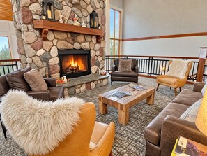 A cozy lobby with a stone fireplace, leather sofas, and a wooden coffee table.