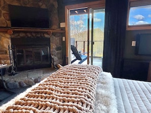 Una habitación con chimenea de piedra, un ventanal y vistas al exterior.