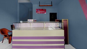 Una zona de recepción con mostrador, un cartel que dice 'Jasmine by Yomoon' y una puerta.