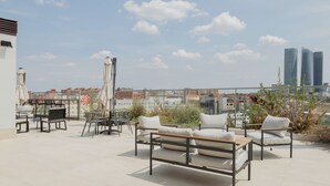 A rooftop terrace with outdoor furniture, including a sofa and chairs, and a table. - Micampus Foronda 7 (Madrid)