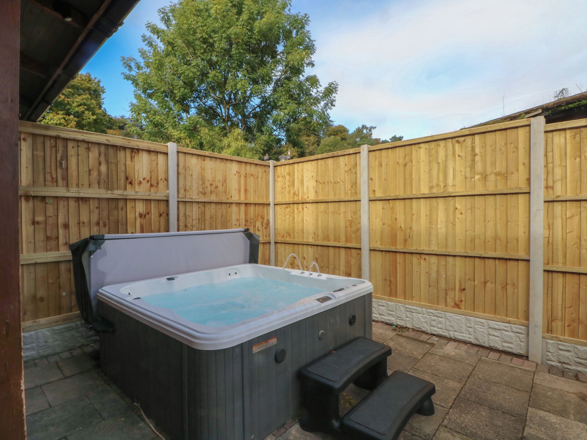Un jacuzzi con cerco de madera y un banco en un patio trasero.