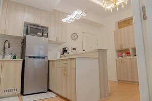 A modern kitchen with a refrigerator, microwave, and coffee maker. - Modern Solace The Florence 1BR (Taguig)