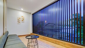 A modern interior with a grey sofa, a small round table with a glass bowl, and a large window with vertical blinds. - Collection O TJ Brother Cengkareng (Jakarta)