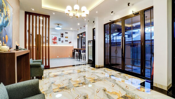 A modern hotel lobby with a marble floor, a reception desk, seating area, and large sliding doors leading to a balcony. - Collection O TJ Brother Cengkareng (Jakarta)