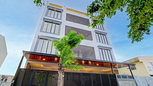 A multi-story building with a modern design, featuring a balcony and a tree in front. - Collection O TJ Brother Cengkareng (Jakarta)