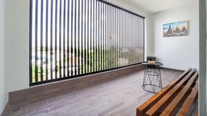 A balcony with a view of greenery, a wooden bench, a small round table, and a painting on the wall. - Collection O TJ Brother Cengkareng (Jakarta)