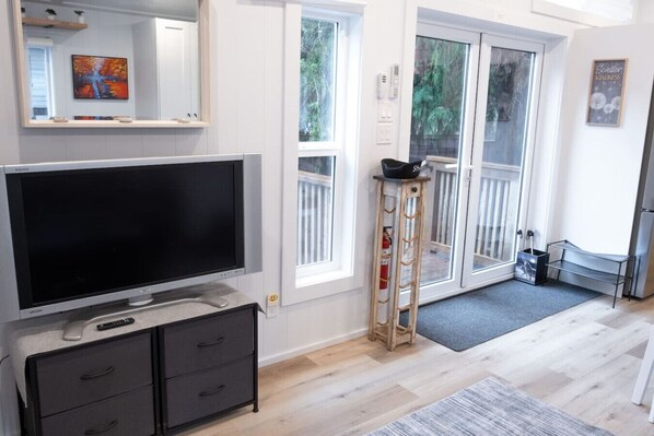 A modern living room with a flat-screen TV, a wooden ladder, and a small table. - The Käbin | Cozy 2BR Cabin (Sunshine Valley)
