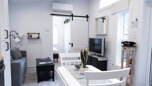 Un espacio habitable pequeño con un sofá, una mesa de comedor, un televisor y un mueble.