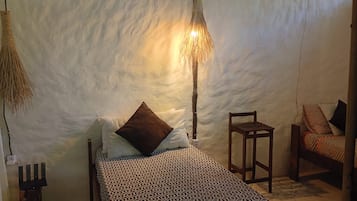 Une pièce comprenant un lit, une chaise, une lampe suspendue et un luminaire fixé au mur.