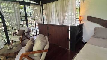 A room with a bed, a sofa, a desk, and a window with curtains.