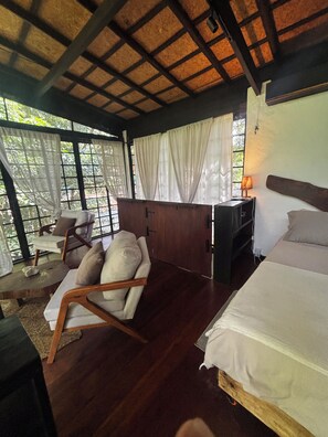 A room with a bed, a sofa, a desk, and a window with curtains.
