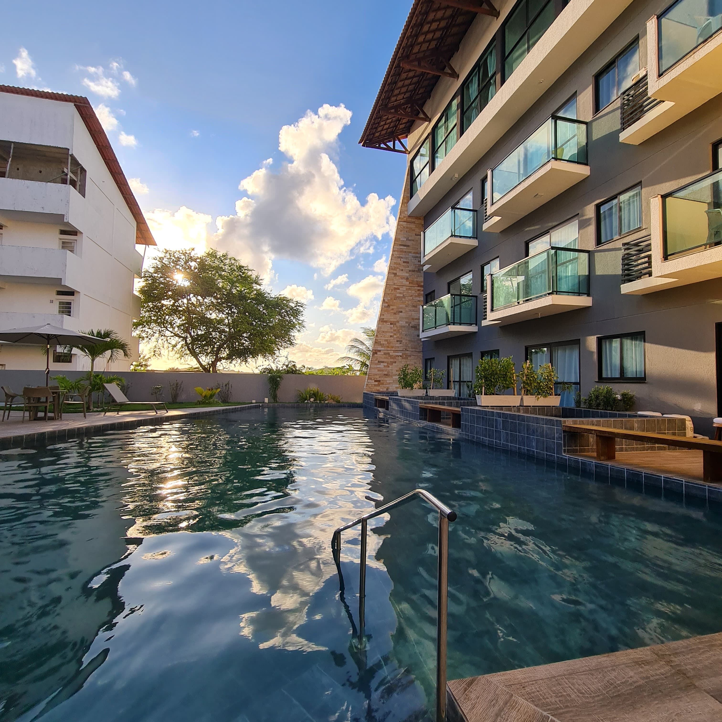 Una piscina con una escalera metálica, rodeada de edificios con balcones y terrazas.