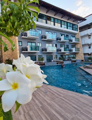 A modern hotel with a swimming pool, outdoor seating, and a view of the building's exterior. - Duplex Luxo 311C Bela Vista by La Playa (Ipojuca)