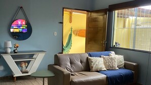 A living room with a sofa, armchairs, a coffee table, a TV mounted on the wall, and a window with bars. - Cozy house near the beach (Barra dos Coqueiros)