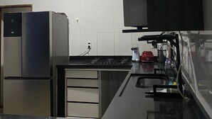 A compact kitchen with a refrigerator, stove, and sink. - Cozy house near the beach (Barra dos Coqueiros)