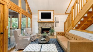 A cozy living room with a stone fireplace, wooden beams, and a large window. - NEW LISTING SPECIAL-Mountain Escape Near It All sleeps 8 with 4 bedrooms! (Sevierville)