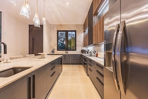 A modern kitchen with a large island, stainless steel appliances, and pendant lighting. - Private Luxury Villa in Nosara. (Playa Pelada)