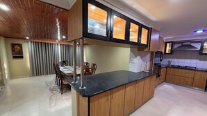 Une cuisine moderne avec des meubles en bois, un plan de travail en granit et un coin repas comprenant une table et des chaises.