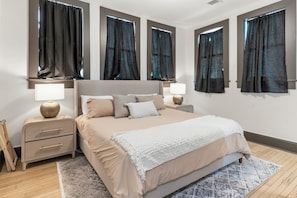 A bedroom with a bed, bedside tables, lamps, and curtains.