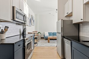 A modern kitchen with a stove, microwave, and refrigerator. There is a dining area with a table and chairs.