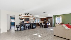 Una cucina moderna con isola centrale, sgabelli da bar e frigorifero.