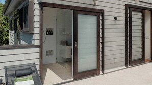 Une maison moderne dotée d’un patio couvert, de grandes portes-fenêtres coulissantes et d’un espace extérieur aménagé pour se détendre.