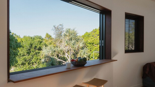 Une pièce avec une grande fenêtre, une petite table et une plante en pot.
