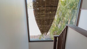 Un escalier en bois avec une rampe, menant à un balcon d’où l’on peut admirer la verdure.