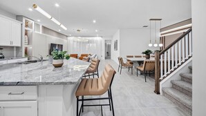 Una cocina moderna con encimera de mármol, armarios empotrados y una isla central con taburetes de bar.