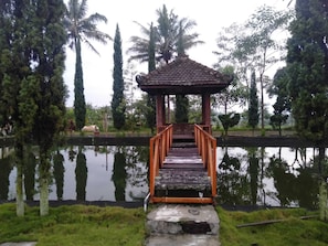 Ein Pavillon mit einer Holztreppe, umgeben von Wasser und Bäumen.
