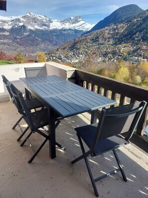 Ein Balkon mit Tisch und Stühlen mit Blick auf eine gebirgige Landschaft.