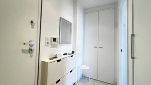Ein modernes Badezimmer mit weißen Schränken, einem Spiegel, einem kleinen Hocker und einer wandmontierten Bedienkonsole.