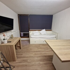 A small, tidy room with a bed, a desk, a TV, and a window. - Studio at the foot of the slopes in Superbesse (Besse-et-Saint-Anastaise)