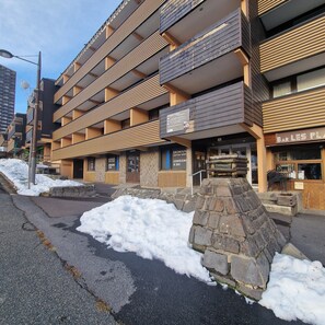 A multi-story building with a stone facade, a visible sign for 'Bar Les Pla', and a 'Consigne à Ski' sign indicating a ski rental service. - Studio at the foot of the slopes in Superbesse (Besse-et-Saint-Anastaise)