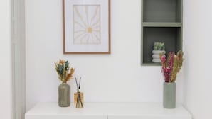 Ein weißer Konsolentisch mit zwei Vasen voller getrockneter Blumen und Rattan-Diffusoren.